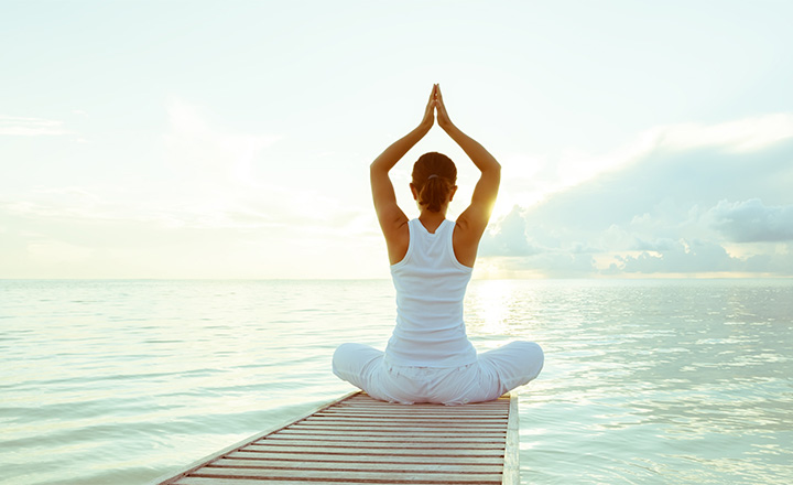 Woman in a yoga pose on a beautiful jetty overlooking a lake