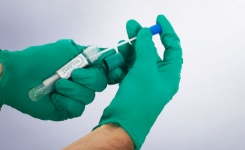 Gloved hands holding a NEMIS Listeria N Light swab